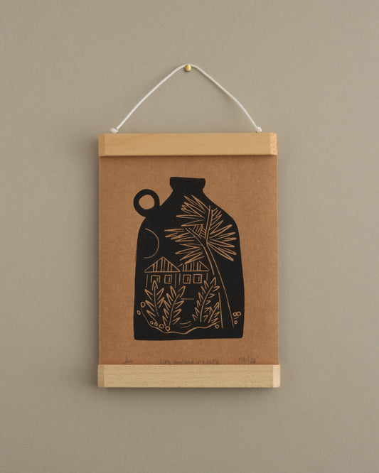 Framed artwork with a black vase design on brown paper against a beige wall