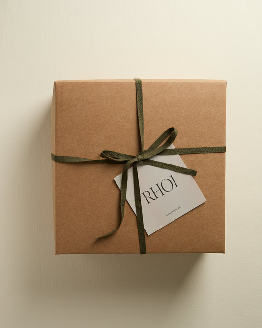Brown gift box with green ribbon and 'RHOI' tag on a beige background
