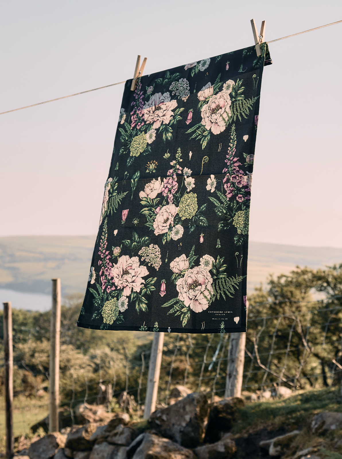 Floral-patterned towel hanging on a clothesline with a scenic background