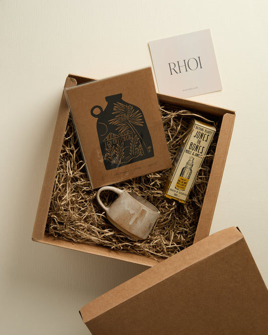 Gift box with a bottle, soap, and a card inside on a beige background